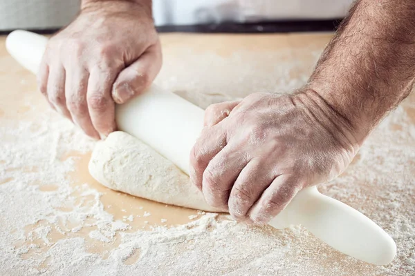 Baker hands knead dough in bright kitchen