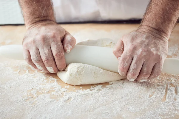 Baker hands knead dough in bright kitchen