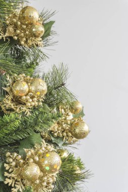 Close-up of Christmas tree in green colors and golden ornaments on white background`