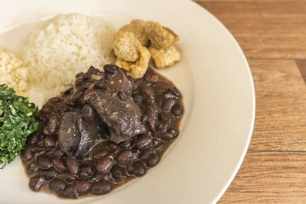 Prato branco com ingredientes de feijoada, comida típica do Brasil — Fotografia de Stock