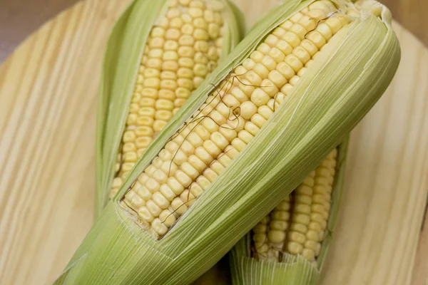 Närbild av rå majs COBS med halm över trä — Stockfoto