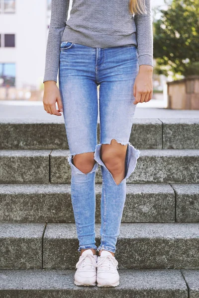 Distressed denim ripped jeans with holes exposing knees of girl — Stock Photo, Image