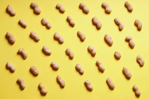 Rijen van pinda's gerangschikt op gele achtergrond — Stockfoto