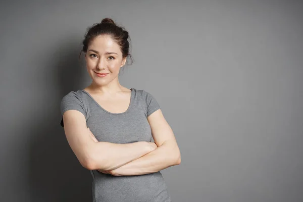 Junge Frau mit zufriedenem Lächeln und verschränkten Armen — Stockfoto