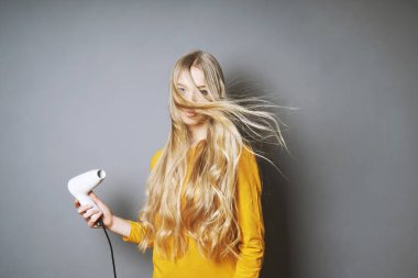 Genç sarışın kadın saçlarını blow-drying