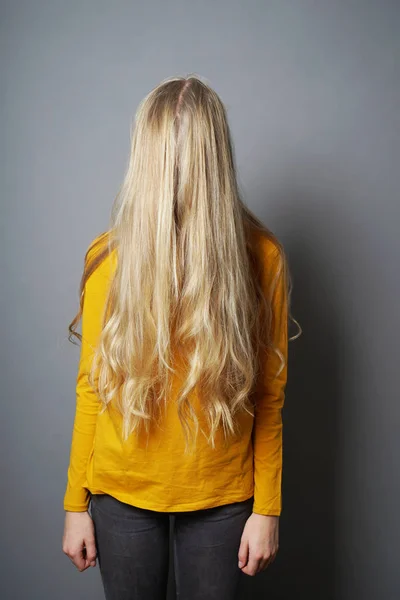 Sjenert ung kvinne med skjult ansikt bak langt blondt hår – stockfoto