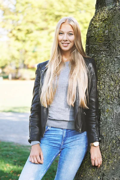 Junge Frau lehnt in Park an Baum — Stockfoto