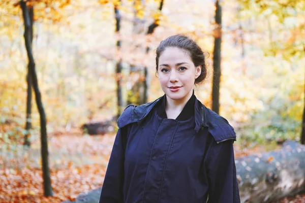 Jonge vrouw genieten van wandeling door bos in de herfst — Stockfoto