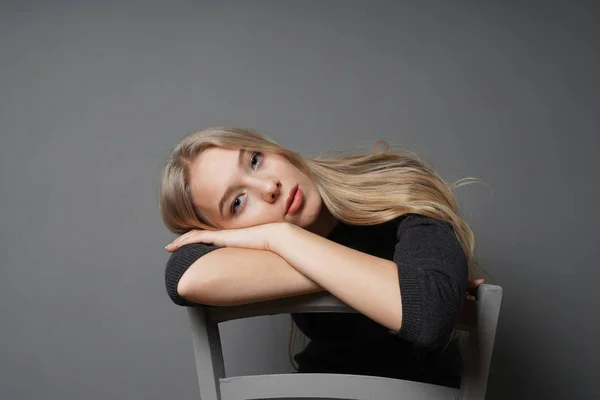 Entediado jovem mulher sentado passeio na cadeira com a cabeça descansando no encosto — Fotografia de Stock