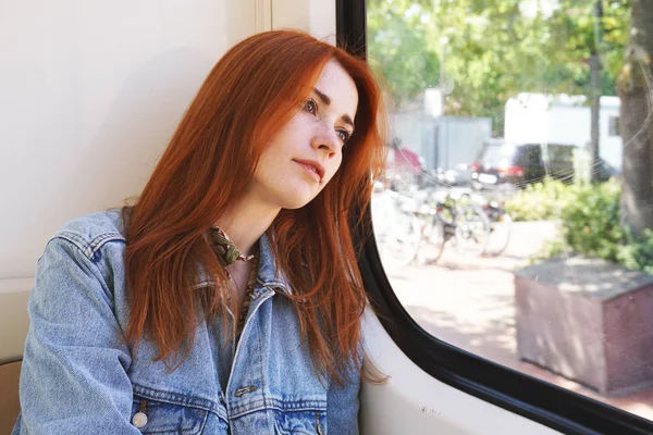 Mujer joven sentada en tranvía o tranvía mirando por la ventana —  Fotos de Stock