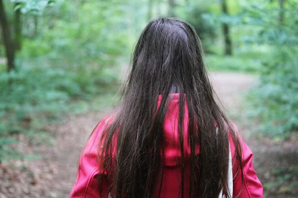 Rear view of unrecognizable young woman during a walk in the woods — Stock Photo, Image