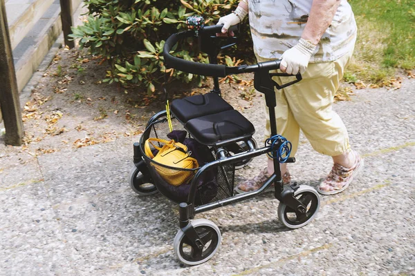 Ηλικιωμένη γυναίκα που περπατάει έξω με κυλιωτή ή τροχήλατο περιπατητή — Φωτογραφία Αρχείου