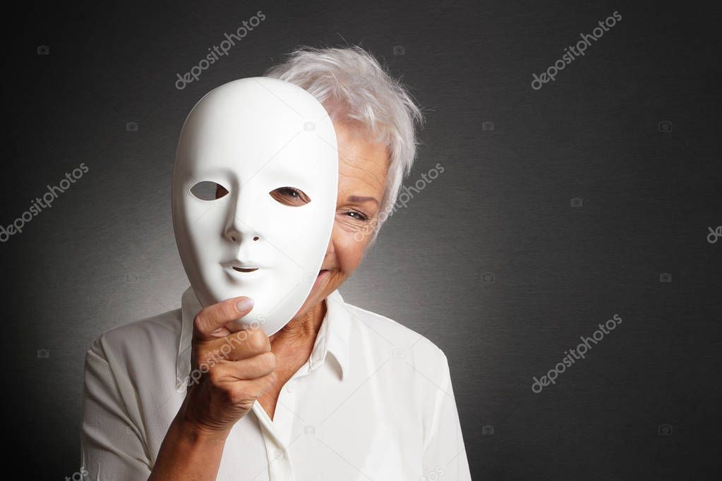 happy senior woman peeking from behind mask