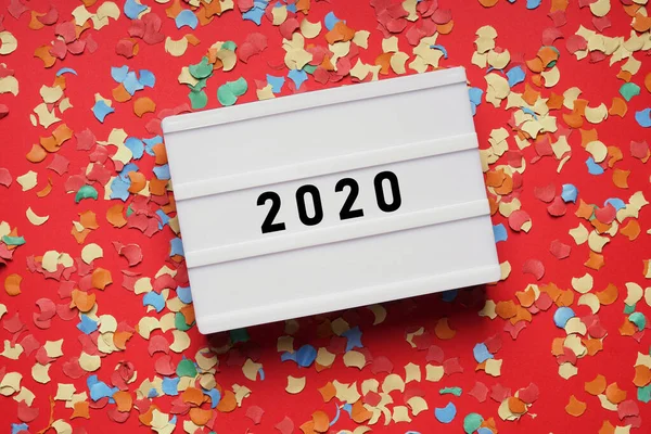 Year 2020 lightbox sign on red paper background with confetti — Stock Photo, Image