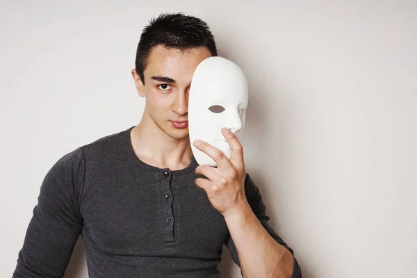 Genç adam beyaz maskeyi çıkarıyor, yüzünü ve kimliğini gösteriyor. — Stok fotoğraf