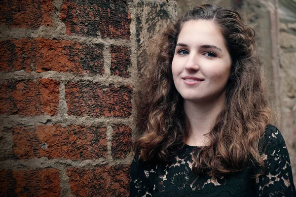 Feliz sorrindo menina encostado contra parede de tijolo velho — Fotografia de Stock