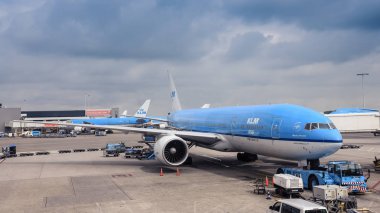 Amsterdam / Hollanda - 07.09.2017: Klm uçak Boeing 777 terminal içinde belgili tanımlık geçmiş koyu mavi bulutlar ile Schiphol Havaalanı'na hazır,. 