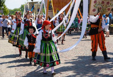 Lowicz / Polonya - 31.2018 olabilir: Corpus Christi kilise tatil alayı. Halk, renkli çizgili bölgesel kostümler giymiş kadınların folklor sembolleri, beyaz gömlek işlemeli. Güneşli gün. 