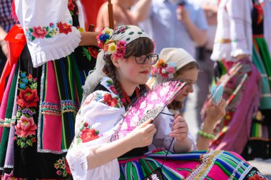 Lowicz / Polonya - 31.2018 olabilir: Corpus Christi kilise tatil alayı. Halk, renkli çizgili bölgesel kostümler giymiş kadınların folklor sembolleri, beyaz gömlek işlemeli. Güneşli gün. 