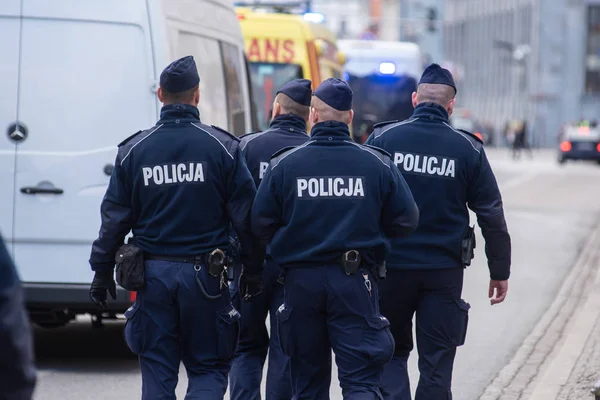 Polis memuru sokakta yürüyen grubu. Polis işaretiyle mavi üniforma giymiş.