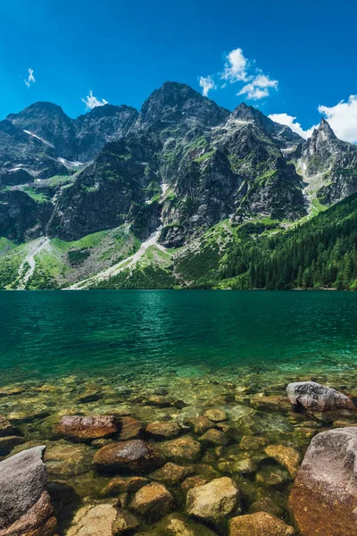 View on the turquoise color lake between high and rocky mountains. Beautiful alpine landscape. 