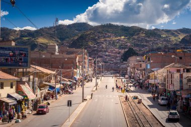 Cusco / Peru - 27 Mayıs 2008: Güneşli bir günde tepeye çıkan şehir caddesini görüntüleyin. Sokakta turuncu renkli çatılar ile evlerin yerel mimarisi. Mavi gökyüzü ve bulutlar.