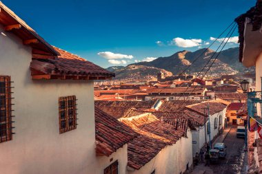 Cusco / Peru - 27 Mayıs 2008: Gün batımında şehir merkezindeki evler arasındaki dar şehir caddesini görüntüleyin. Turuncu renkli çatı ile evler ile yerel mimari. Mavi gökyüzü ve bulutlar.