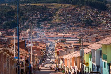 Cusco / Peru - 27 Mayıs 2008: Güneşli bir günde tepeye çıkan şehir caddesini görüntüleyin. Sokakta turuncu renkli çatılar ile evlerin yerel mimarisi. Mavi gökyüzü ve bulutlar.