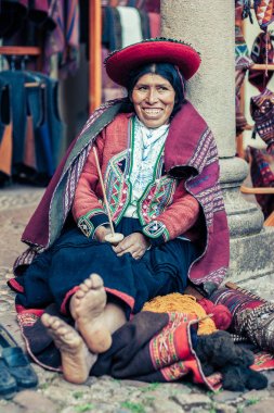 Cusco / Peru - Mayıs 26.2008: Bir kanalizasyon kadın Portresi, terzi, geleneksel yerli Perulu giysiler giyinmiş. Yalınayak sokakta oturma, gülümseyerek dikiş araçları tutarak. 