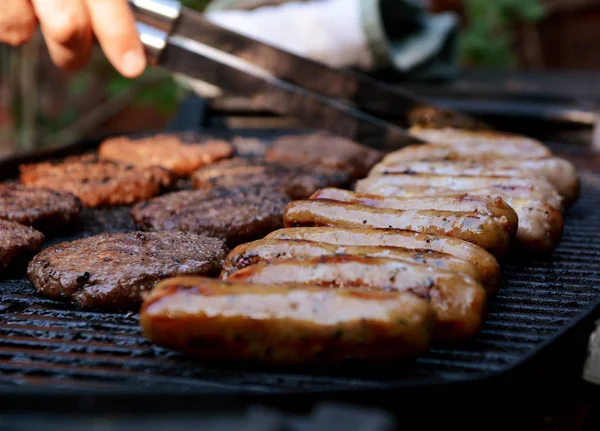 Sausages Hamburgers Barbecue Grill Cook Uses Tongs Background — Stock Photo, Image