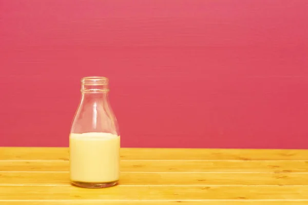 Ένα Τρίτο Γυάλινο Μπουκάλι Γάλα Μισογεμάτο Μιλκσέικ Μπανάνας Ξύλινο Τραπέζι — Φωτογραφία Αρχείου