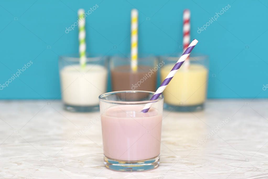 Strawberry milkshake in front of a row of flavoured milkshakes