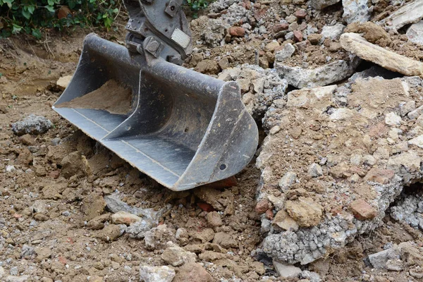 Cubo de excavadora de metales de servicio pesado entre montones de escombros ásperos —  Fotos de Stock