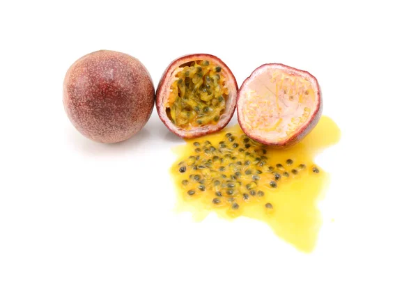 Frutas de la pasión enteras y cortadas a la mitad con jugo y semillas derramadas — Foto de Stock