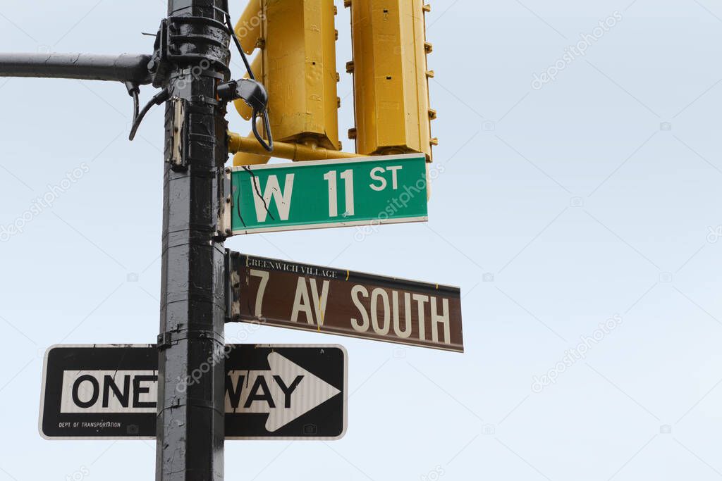Street signs on the corner of 7th Ave South and West 11th Street in Greenwich Village, New York City; copy space on blue sky