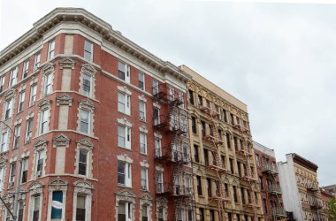 NEW YORK, ABD - 10 Mayıs 2019: Carmine Caddesi ve Bleecker Caddesi 'nin köşesindeki apartmanlar 10 Mayıs 2019 tarihinde. Süslü tuğla ve yangın merdivenleri özellikle göze çarpıyor..
