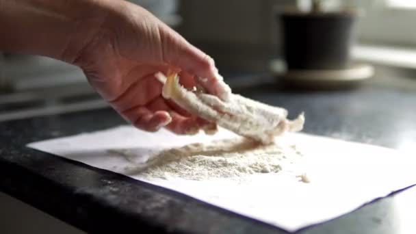 妇女的手在桌子上的鱼片上涂面粉和盐的特写镜头 — 图库视频影像