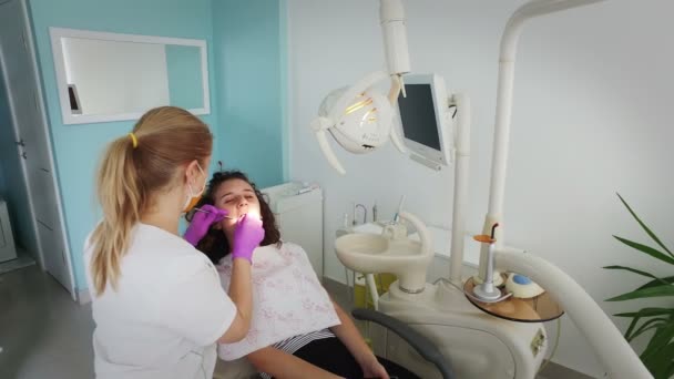 プロの歯のクリーニング歯科医院でメスの若い患者を作る歯医者 — ストック動画