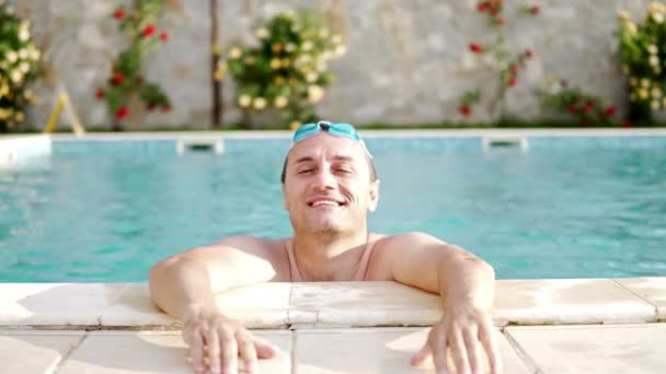 晴れた日にはスイミング プールでリラックスしたゴーグルと笑みを浮かべて男 — ストック動画