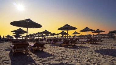 Boş plajda şezlong ve ahşap harika gün batımı tutuyor