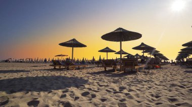 Boş plajda şezlong ve ahşap harika gün batımı tutuyor