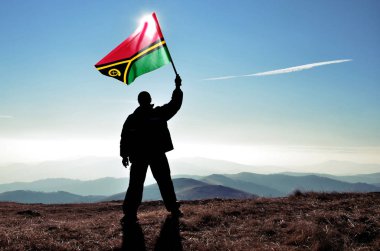dağ tepe üstünde dalgalanan Vanuatu bayrak tutan adam silüeti