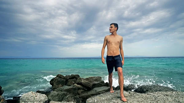 年轻男子摆在岩石上 享受在海洋附近的假期 — 图库照片