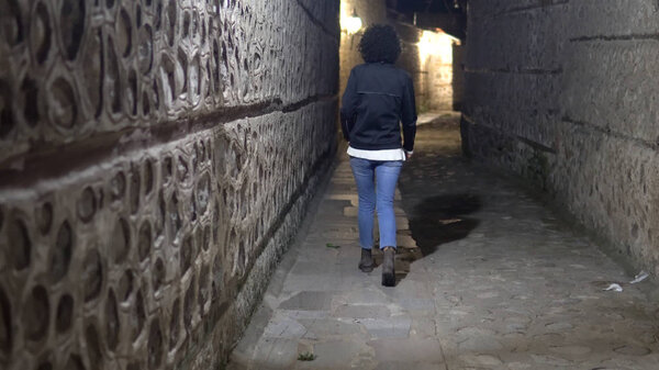 woman model walking in dark alley at night, narrow dirty corner, street in the old town
