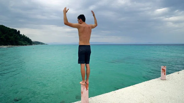 Junger Mann Steht Auf Seebrücke Und Hält Die Hände Hoch — Stockfoto