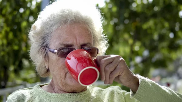 elderly old woman drinking coffee outdoor