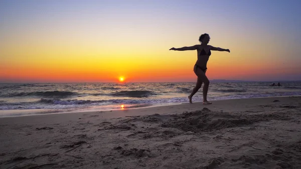 日没の背景 自由の概念にワイド オープンの手で海を歩く女性 — ストック写真