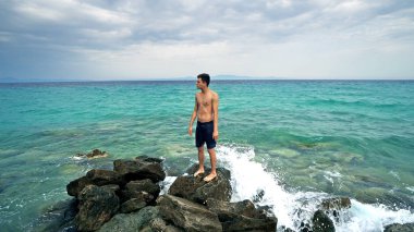 kayaların üzerinde poz ve okyanusu yakınlarındaki tatil zevk genç adam