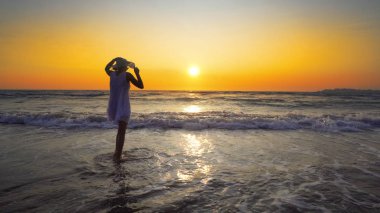 kadın beyaz elbise ve şapka ayakta günbatımı zemin üzerine sahil şeridi üzerinde