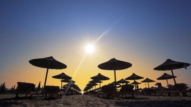 Boş plajda şezlong ve ahşap harika gün batımı tutuyor